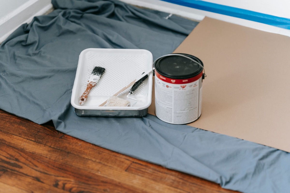 Paint roller and tray on a drop cloth in a room being painted